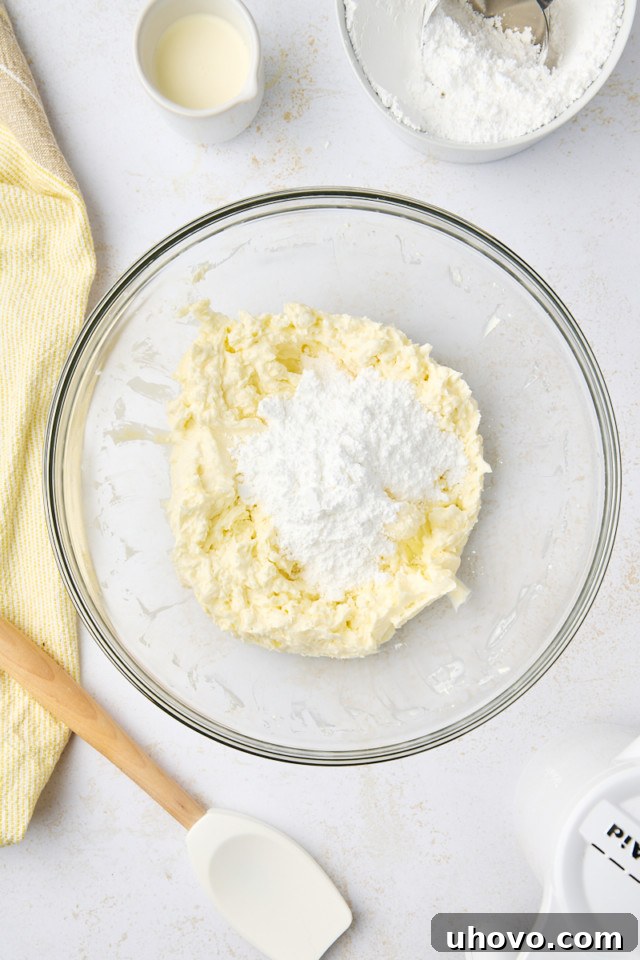 overhead view of confectioners' sugar added to beaten butter and cream cheese