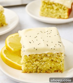 a slice of lemon poppy seed cake on a white plate with more cake in the background