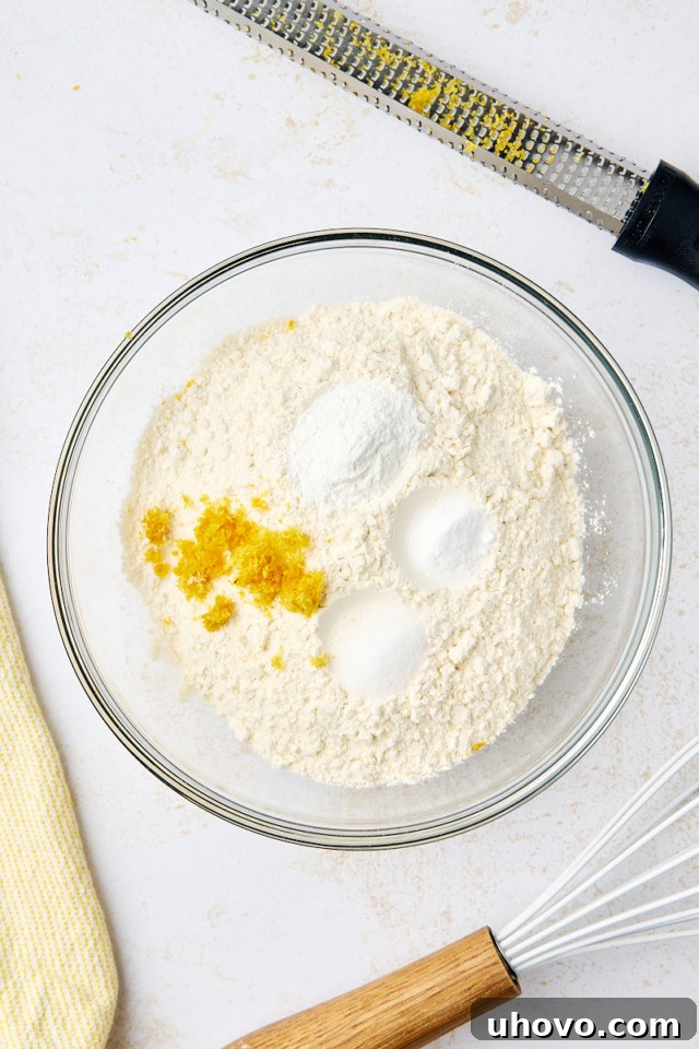 overhead view of flour, baking powder, baking soda, salt, and lemon zest in a mixing bowl