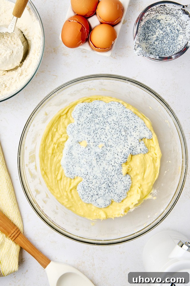 overhead view of buttermilk and poppy seeds added to lemon poppy seed cake batter