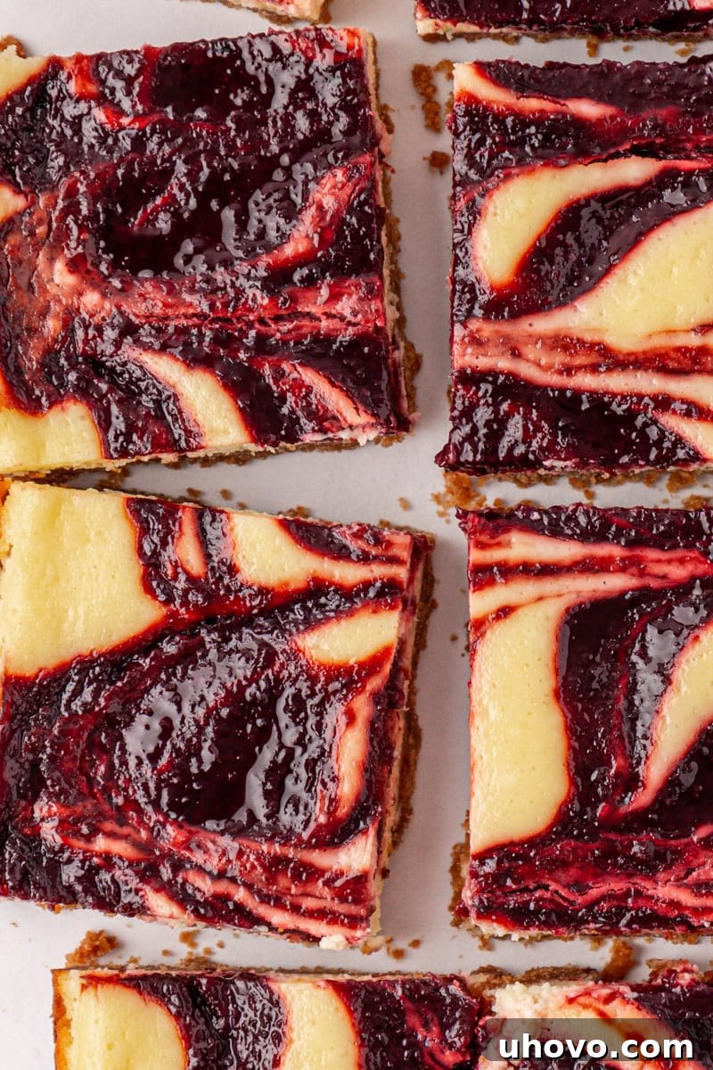 An overhead view of a pan of perfectly sliced cherry cheesecake bars, showcasing the even cuts, vibrant cherry swirls, and golden crusts, ready for serving.