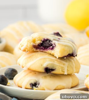 a stack of three lemon blueberry cookies with a bite missing from the top cookie