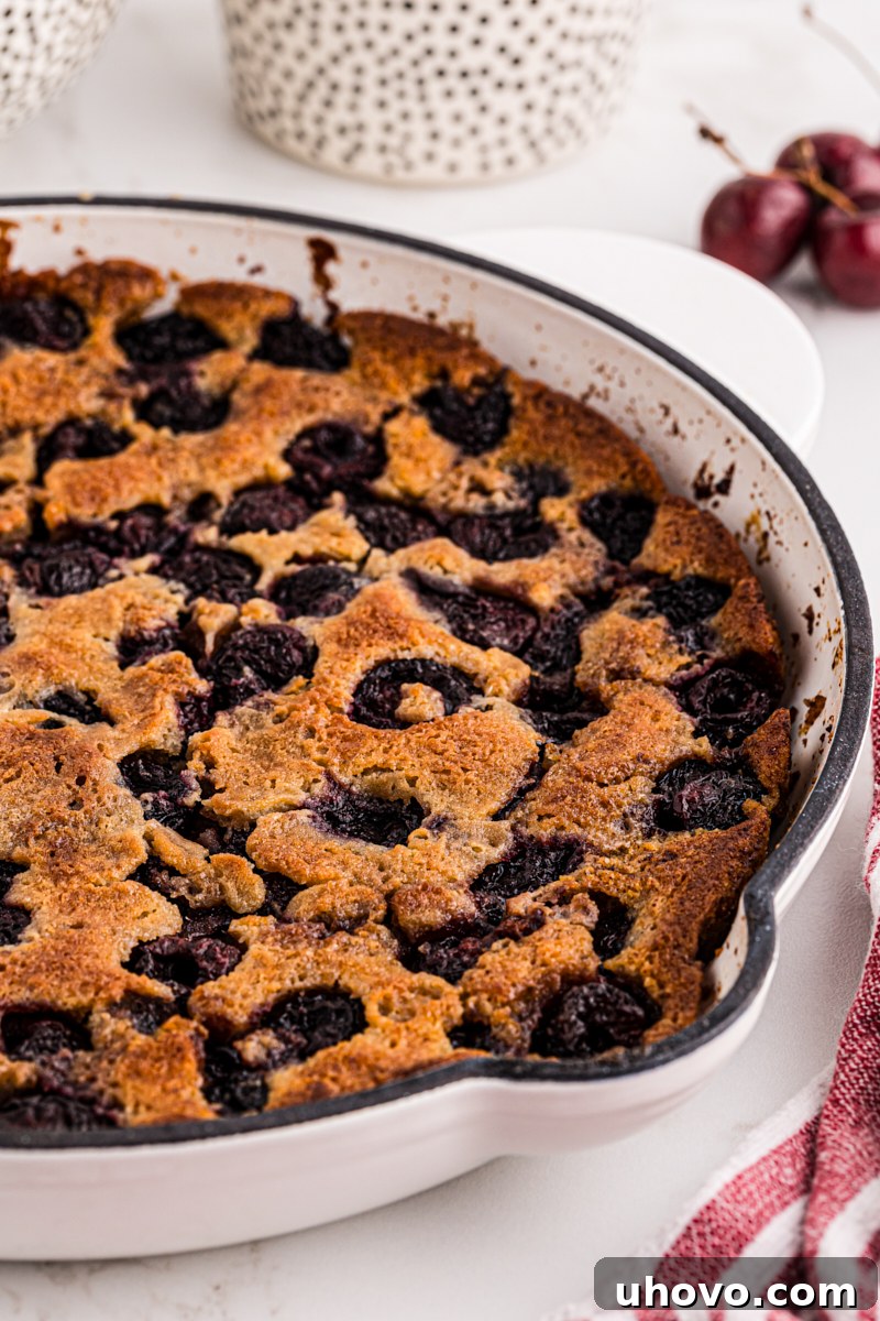 A warm, golden-brown brown butter cherry cobbler presented beautifully in a white cast iron skillet, ready to be served.