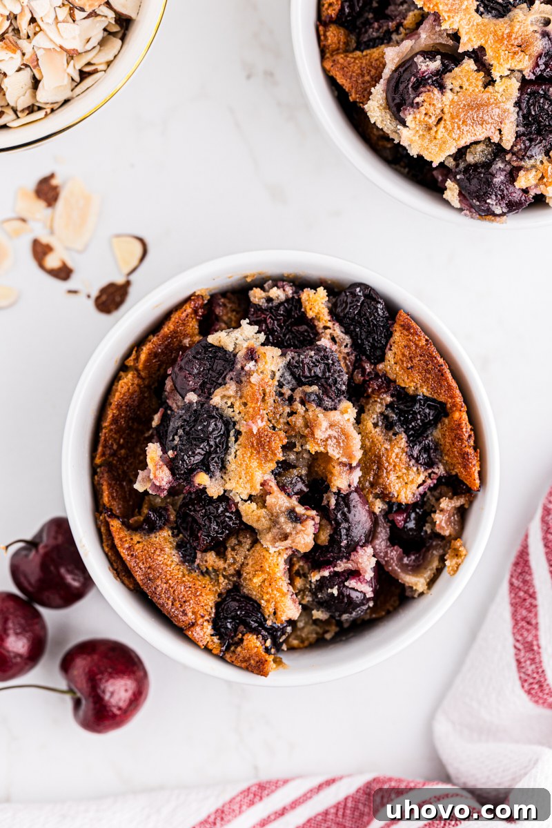Overhead view of a single serving of brown butter cherry cobbler in a bowl, showing the golden crust and vibrant cherry filling.