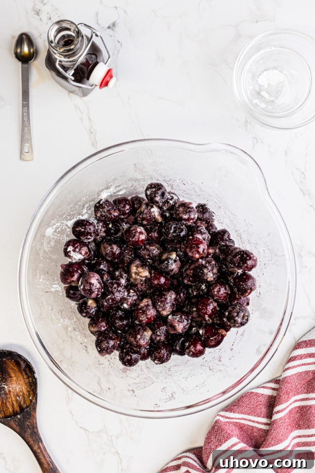 Overhead view of cherry filling in a mixing bowl after stirring, showing evenly coated cherries ready for the cobbler.