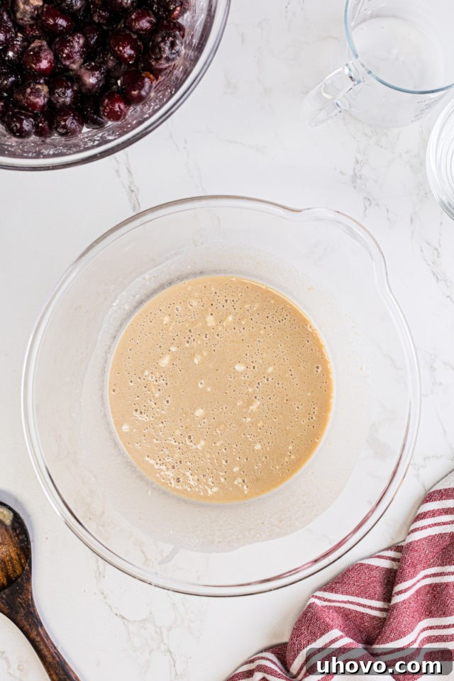 Overhead view of the smooth, pourable batter for the cobbler in a mixing bowl after milk has been added and stirred.