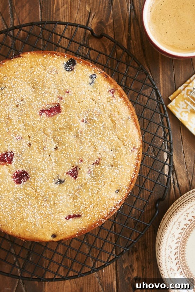 Overhead view of a freshly baked Berry Muffin Cake cooling on a wire rack, sprinkled with powdered sugar.