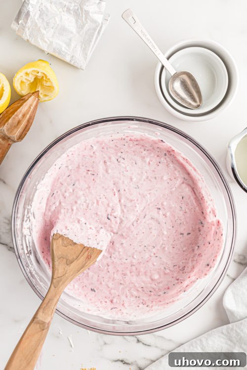 Overhead view of the finished triple berry no-bake cheesecake filling in a glass mixing bowl