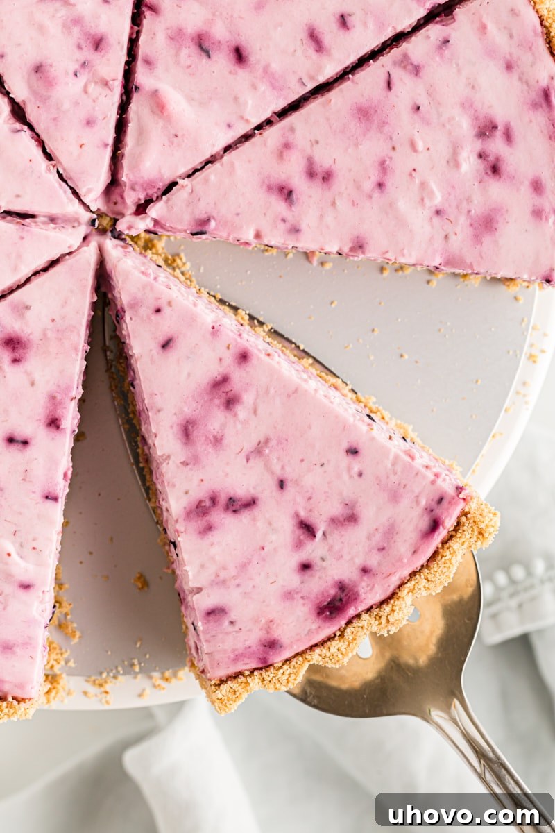 Overhead view of a slice of berry cheesecake being carefully removed from the whole cake