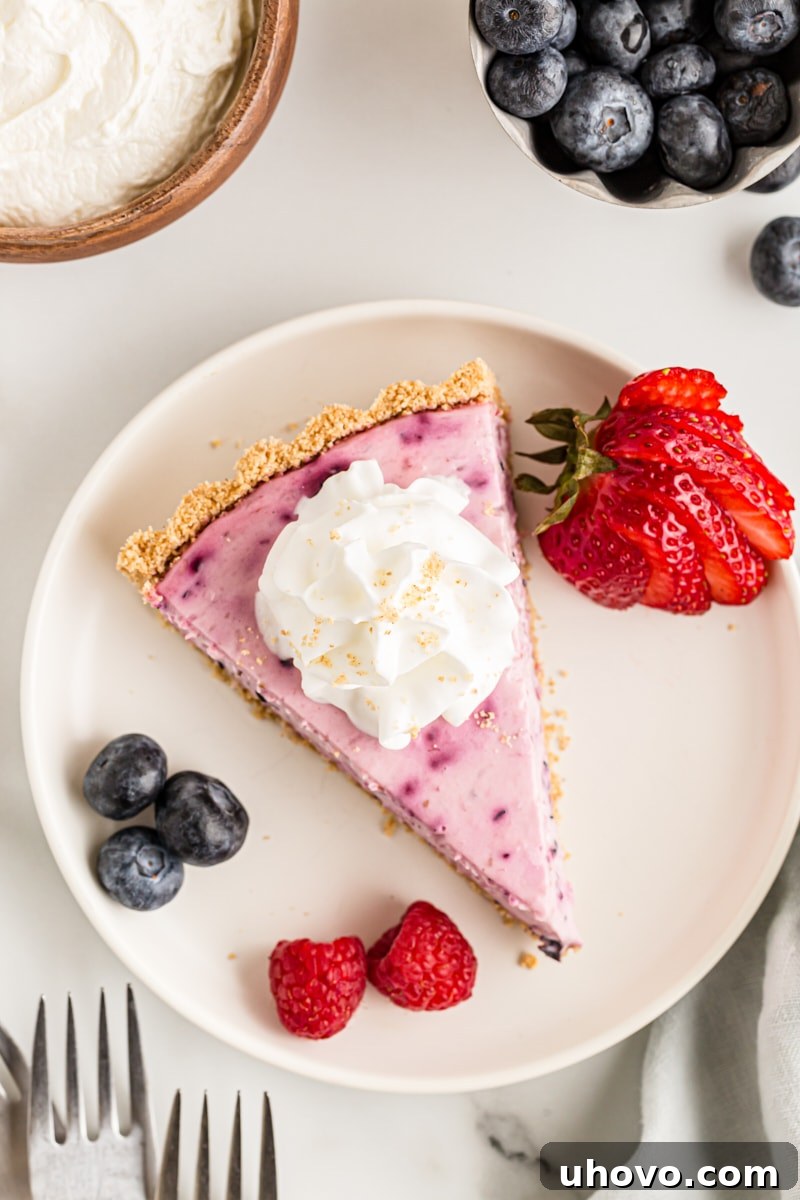 Overhead view of a beautiful slice of triple berry no-bake cheesecake on a plate with fresh berries