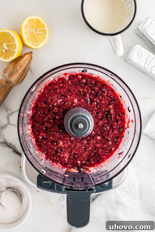 Overhead view of beautifully pureed berries in a food processor, ready for the cheesecake filling