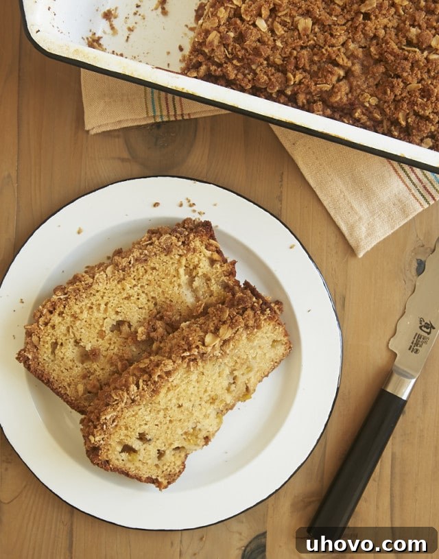 Overhead view of several slices of homemade Peach Streusel Bread on a white plate, garnished with fresh peach slices