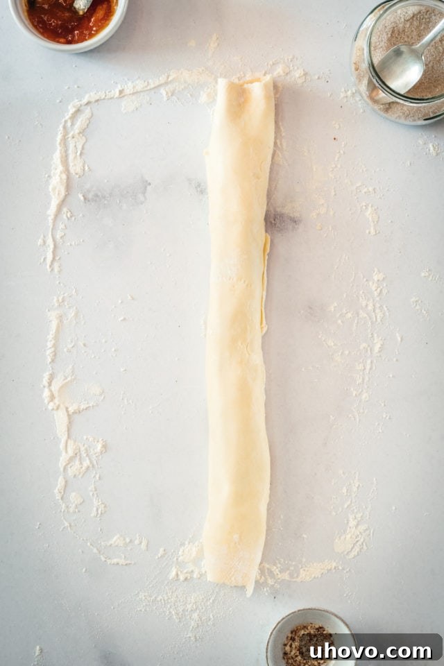 Log of rugelach dough rolled up on marble surface