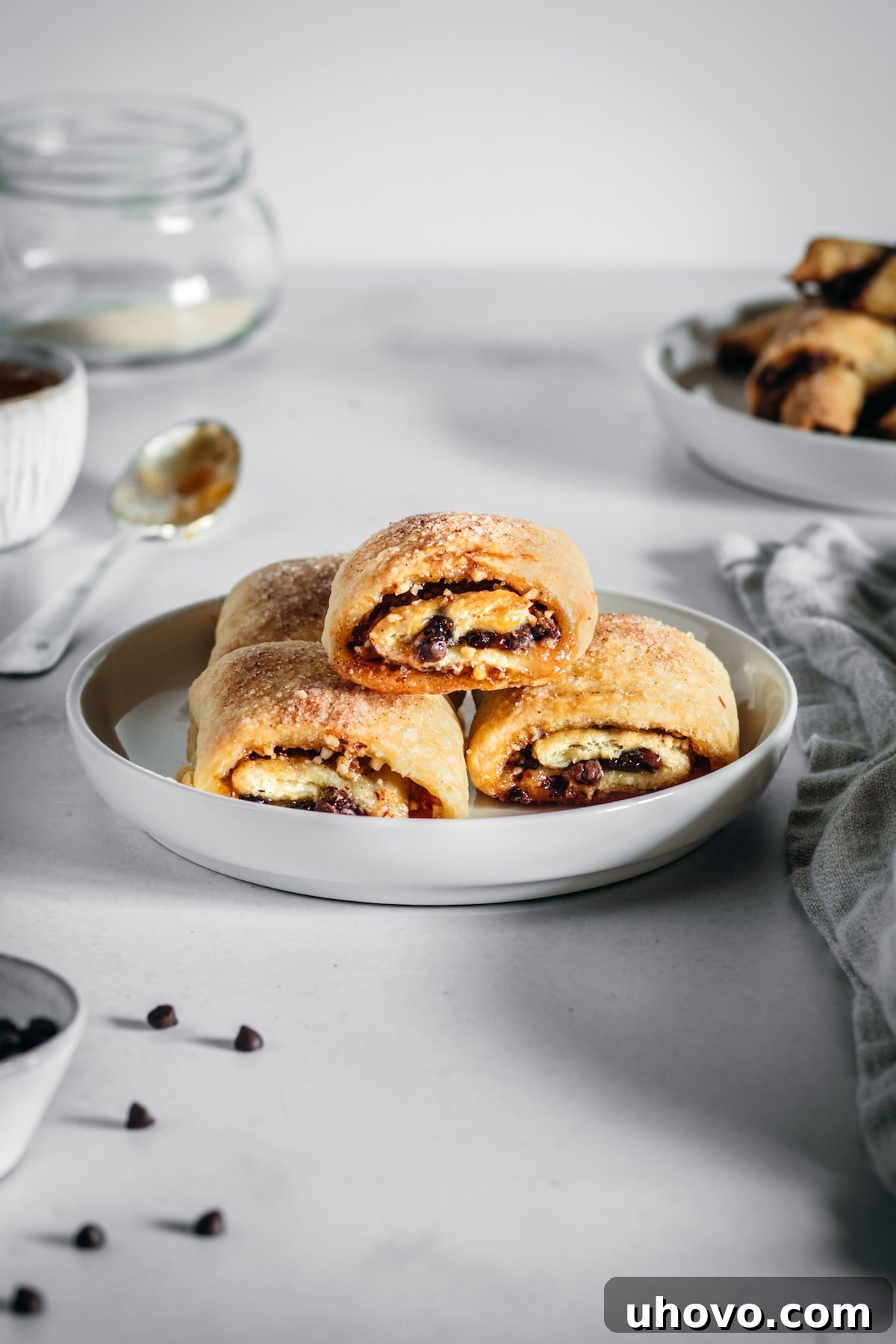 Rectangle rugelach stacked onto a plate with ingredients scattered in background