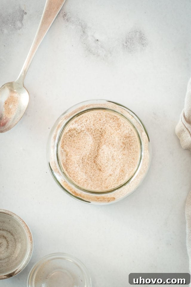 Overhead view of glass jar filled with cinnamon sugar and spoon