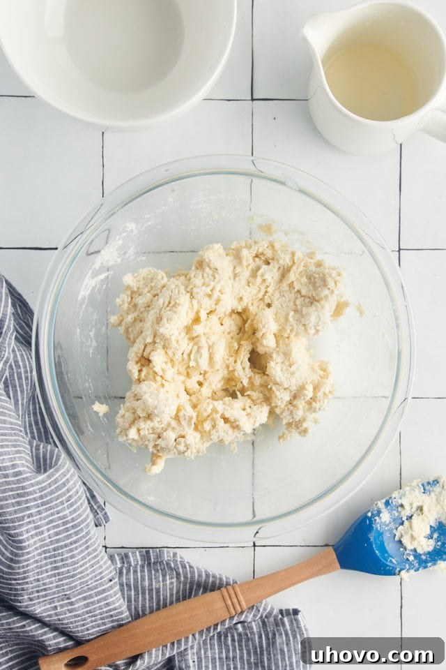 Overhead view of biscuit dough in a glass mixing bowl, just after mixing the cream into the flour.