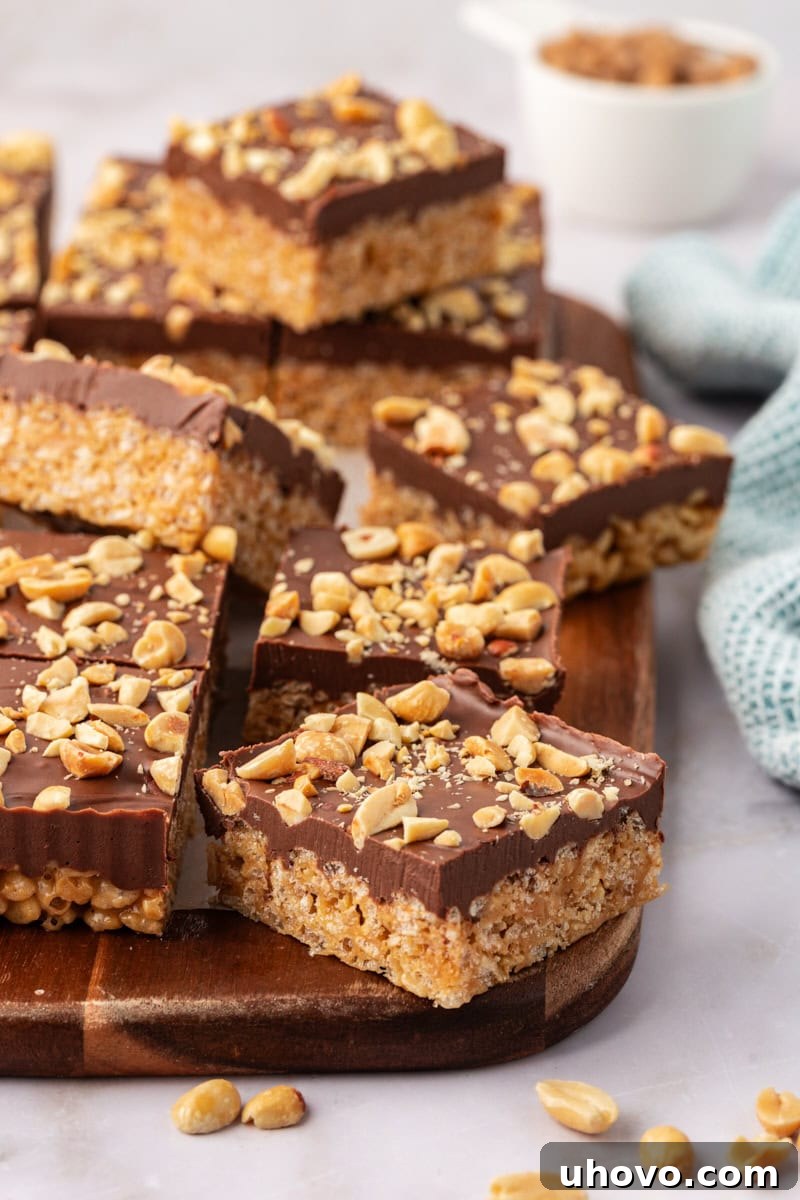 Irresistible chocolate peanut butter rice crispy treats artfully arranged on a rustic wooden cutting board, showcasing their layers of crispy goodness and rich topping.