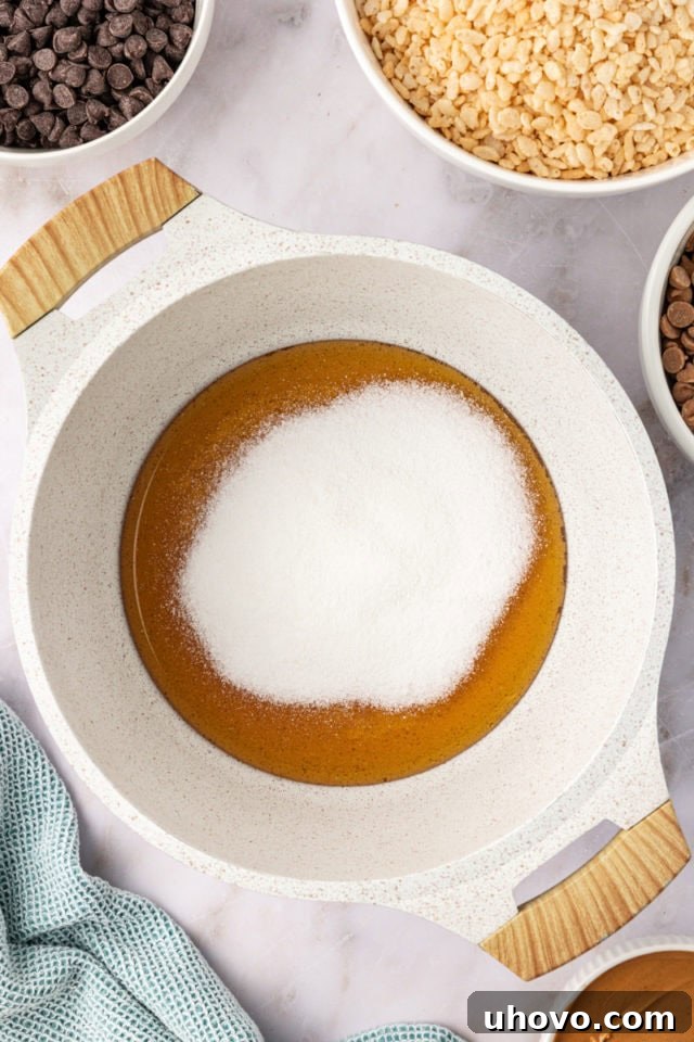 An overhead view of golden honey and white granulated sugar combining in a saucepan, beginning the process of creating the sticky, sweet base for the crispy treats.