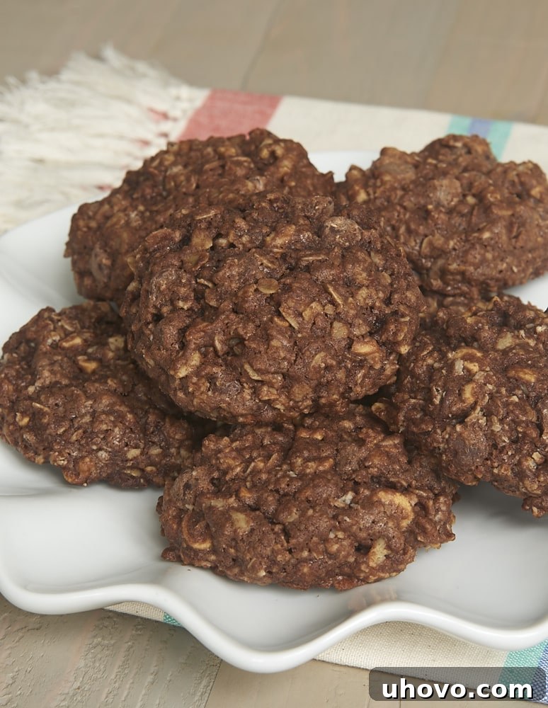 A large pile of rich, fudgy chocolate monster cookies on a plate, showcasing their inviting texture and numerous mix-ins.