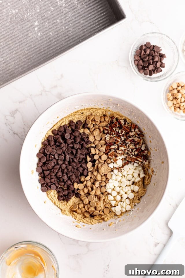 Chocolate chips, white chocolate chips, peanut butter chips, and pecans added to bowl of dough