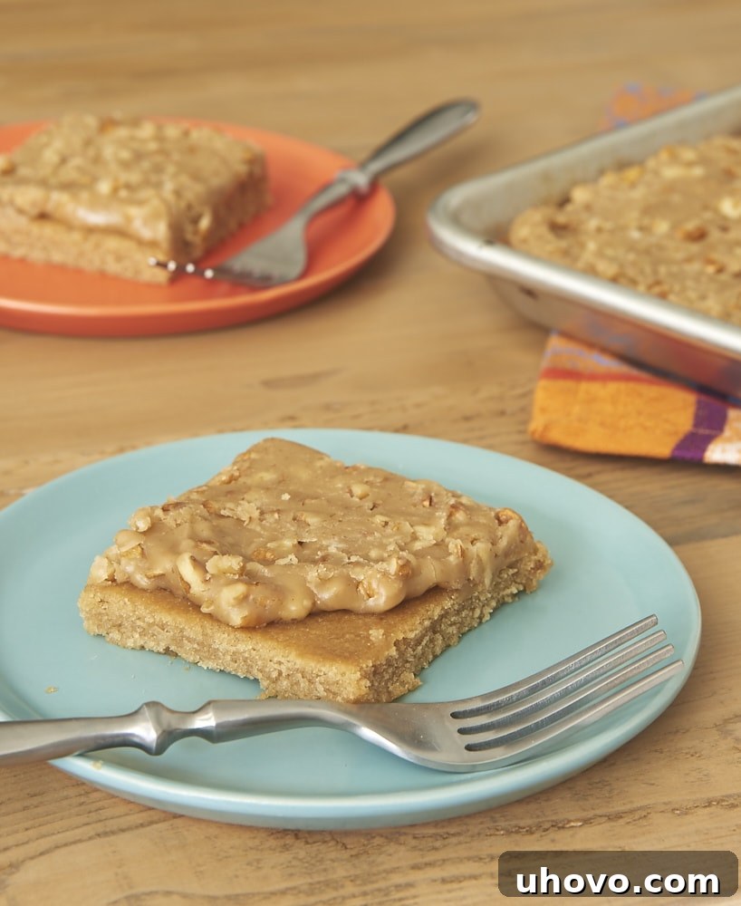 A close-up shot of a slice of Pecan Praline Sheet Cake, highlighting its moist texture and generous praline frosting.