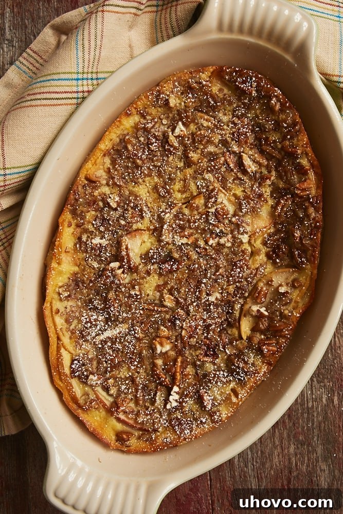 An overhead view of a freshly baked Apple Bourbon Clafoutis, golden brown and puffed in a stoneware baker, ready to be served