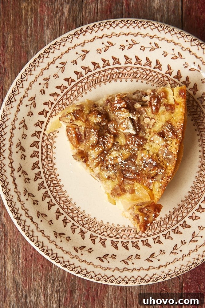 A perfectly sliced portion of Apple Bourbon Clafoutis, revealing its tender apple and custardy layers, presented on a delicate floral plate