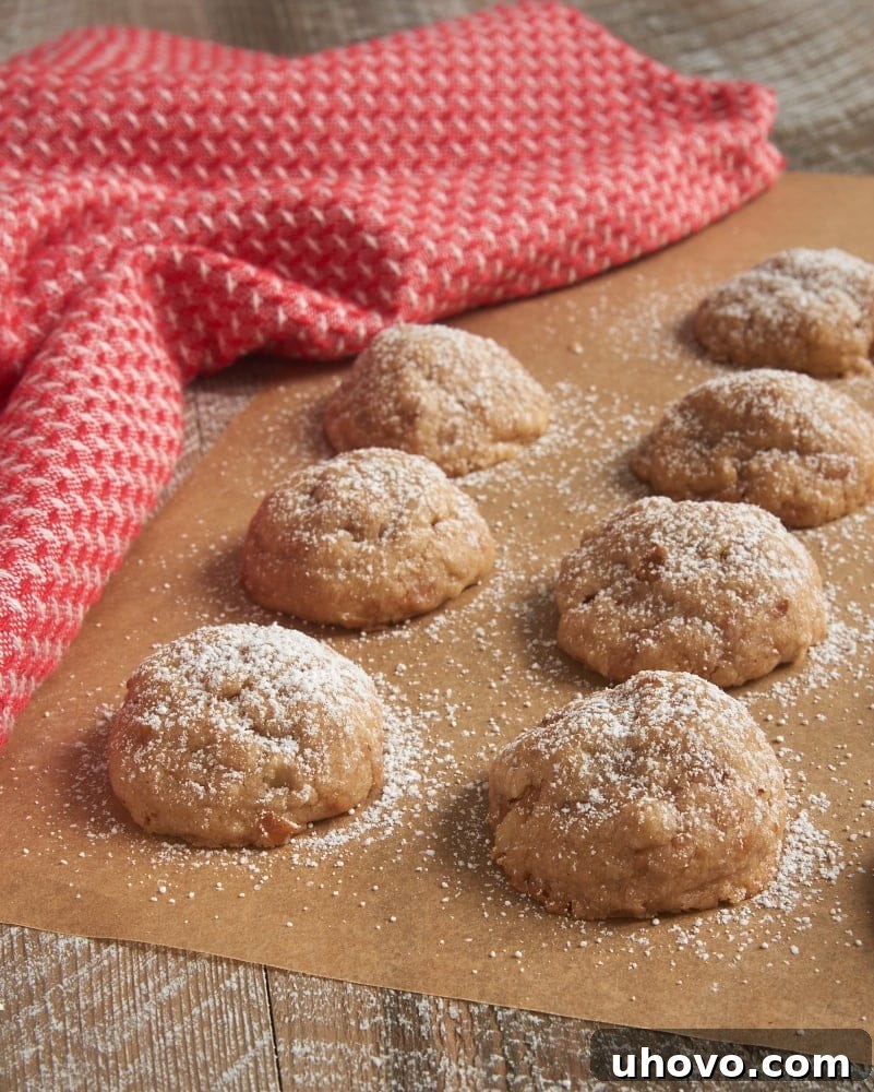 Golden brown Toffee Pecan Snowdrop Cookies cooling on parchment paper, ready to be dusted with powdered sugar.