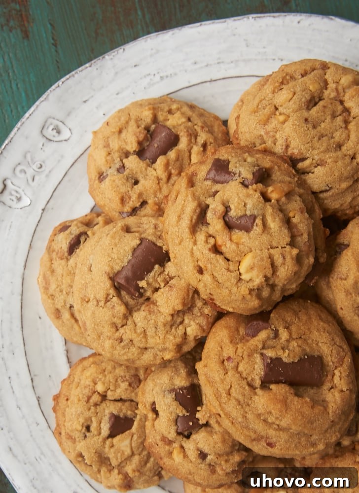 Overhead view of several Peanut Butter Chocolate Chip Crunch Cookies arranged on a white and gray plate, highlighting their golden brown edges and visible chocolate chips and toffee