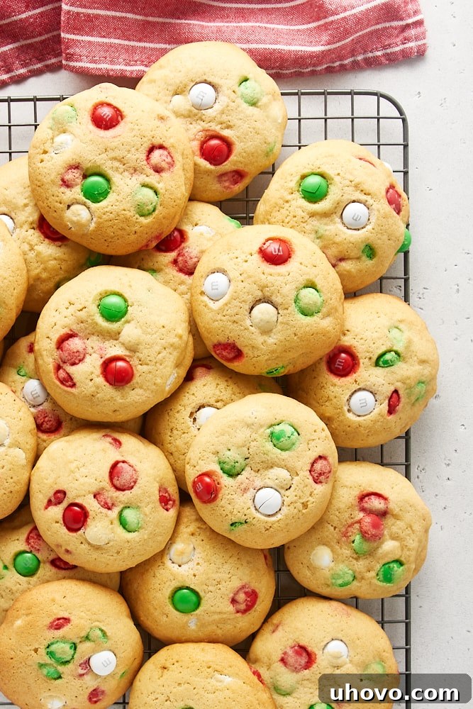Overhead view of M&M Christmas cookies piled on a wire rack.
