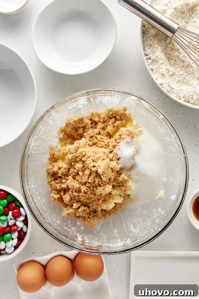 Brown sugar and granulated sugar added to creamed butter in a glass mixing bowl.