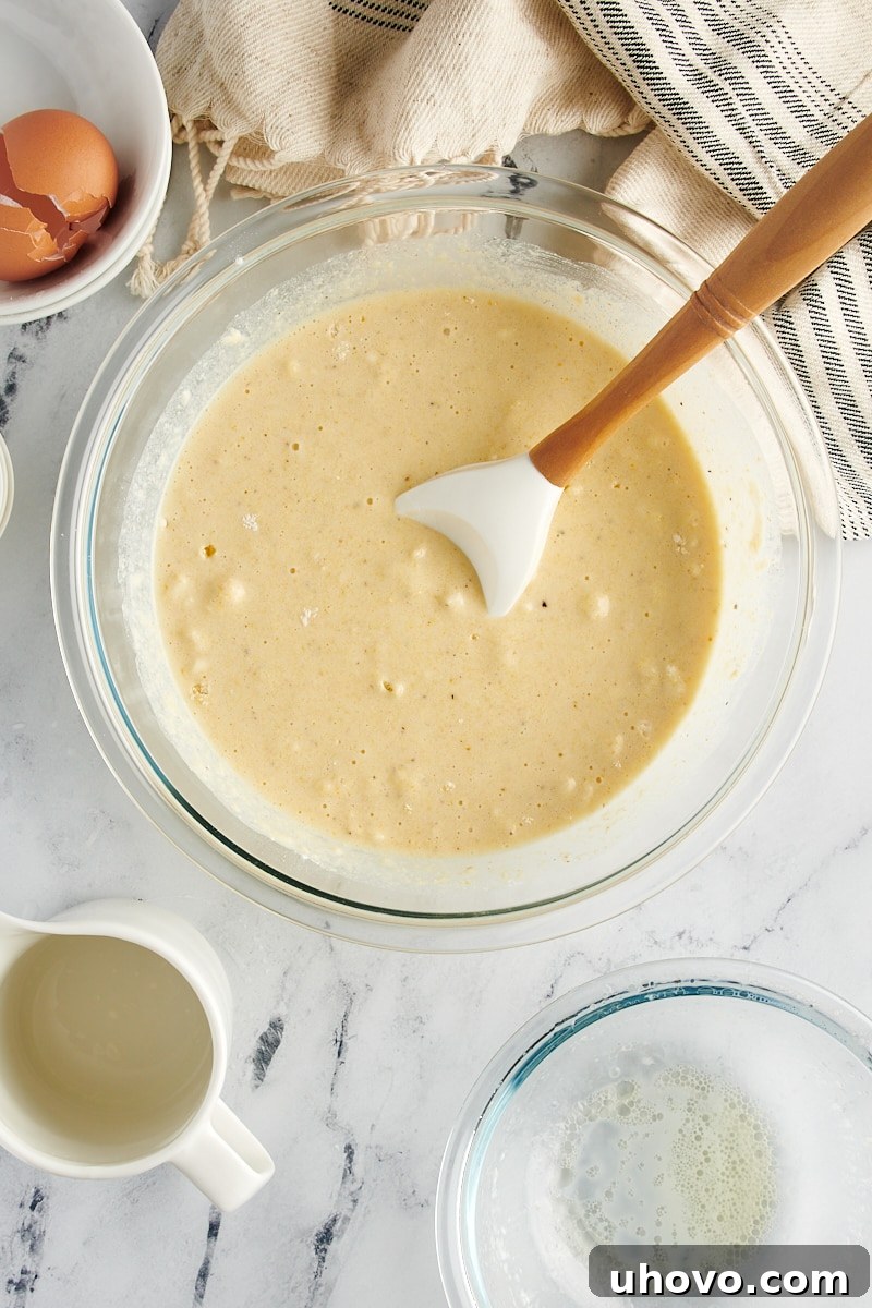 A beautifully textured corn muffin batter, with a few small lumps, perfectly mixed in a glass bowl, ready for baking.