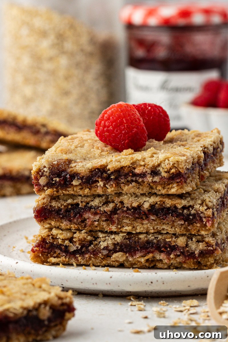 a stack of three raspberry oatmeal bars topped with fresh raspberries