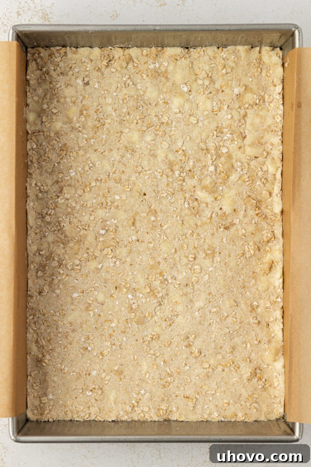 overhead view of raspberry oatmeal bars crust in a parchment-lined baking pan