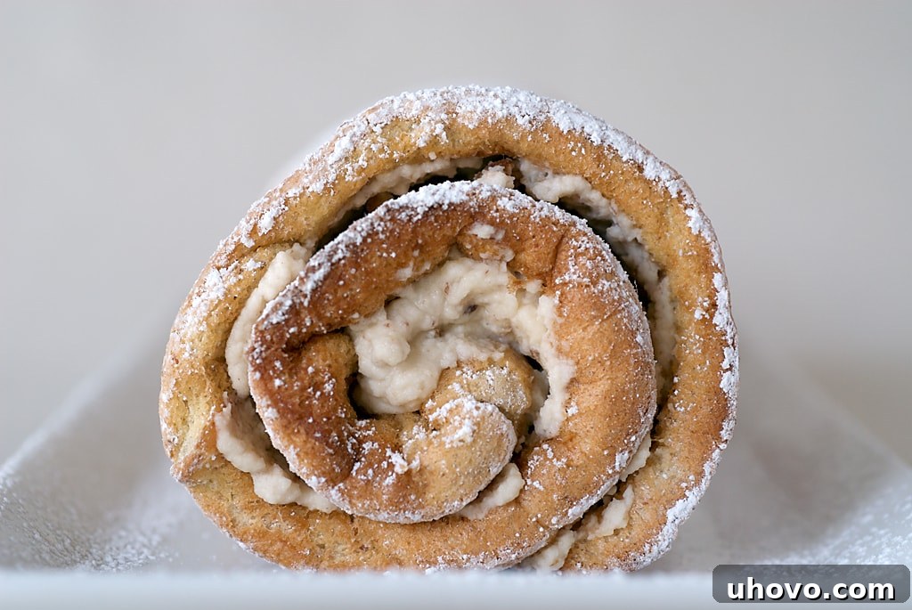 A close-up front view of the Toasted Pecan Roulade, showcasing its perfect spiral and generous filling, elegantly dusted with powdered sugar.