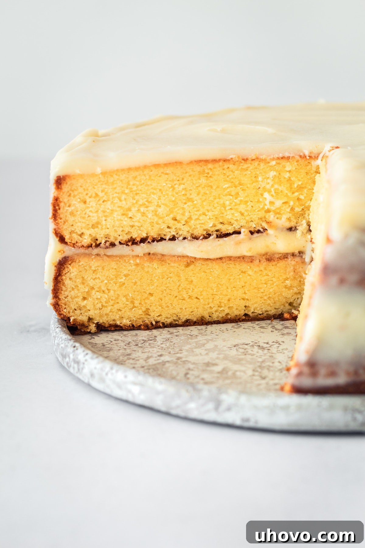A beautifully decorated caramel cake with caramel cream cheese frosting, a slice removed revealing the layered interior. The cake sits elegantly on a stand, hinting at its rich texture and flavor.