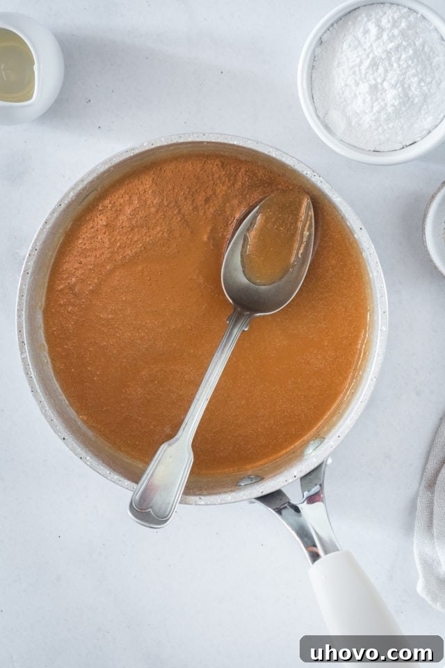 An overhead shot of bubbling caramel in a heavy saucepan on the stovetop, showing the cooking process of brown sugar, evaporated milk, and butter to reach the perfect candy stage.