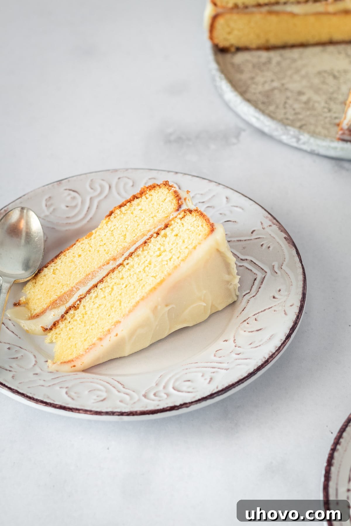 A perfectly portioned slice of caramel cake, topped with a generous swirl of caramel cream cheese frosting, served on a delicate plate with a spoon, ready to be enjoyed.