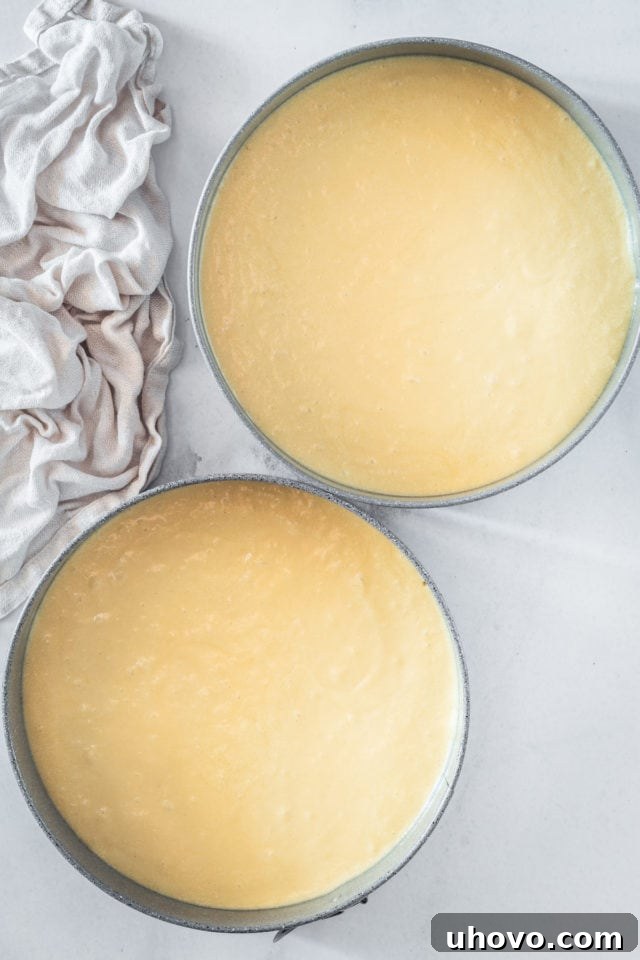 An overhead shot of two caramel cake layers in round baking pans, with the batter evenly divided, ready to be placed in the oven for baking, promising a delicious outcome.