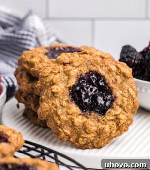 an oatmeal thumbprint cookie leaning against a short stack of more cookies on a white plate