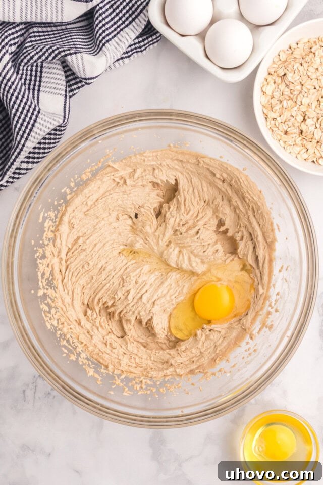 overhead view of egg added to creamed butter and sugars in a glass mixing bowl