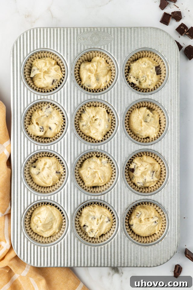 overhead view of chocolate chunk cupcake batter in a muffin pan ready to go into the oven