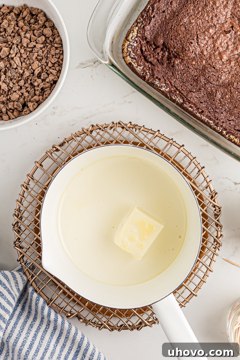 Overhead view of butter and heavy cream in a small saucepan, heating for ganache preparation.