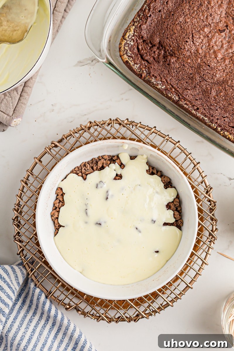 Overhead view of hot cream and melted butter being poured over finely chopped chocolate in a mixing bowl.