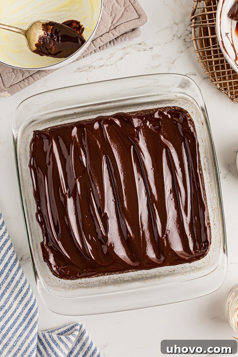 Overhead view of baked brownies after being generously frosted with a thick layer of chocolate ganache.