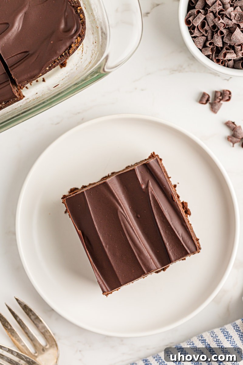 Close-up overhead shot of a single chocolate mascarpone brownie, perfectly cut on a white plate.
