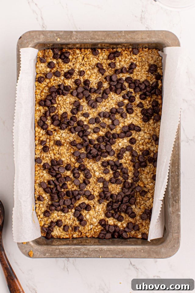 Semisweet chocolate chips sprinkled evenly over the partially baked oatmeal crust.