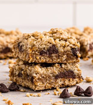 Stack of two perfectly baked caramel oatmeal bars, with rich caramel visible between the oat layers.