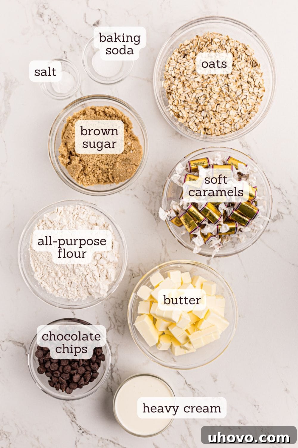 Overhead view of various ingredients laid out for caramel oatmeal bars, including oats, flour, sugar, butter, and caramels.