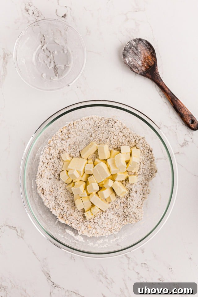 Cold, cubed butter being added to the dry crust mixture.
